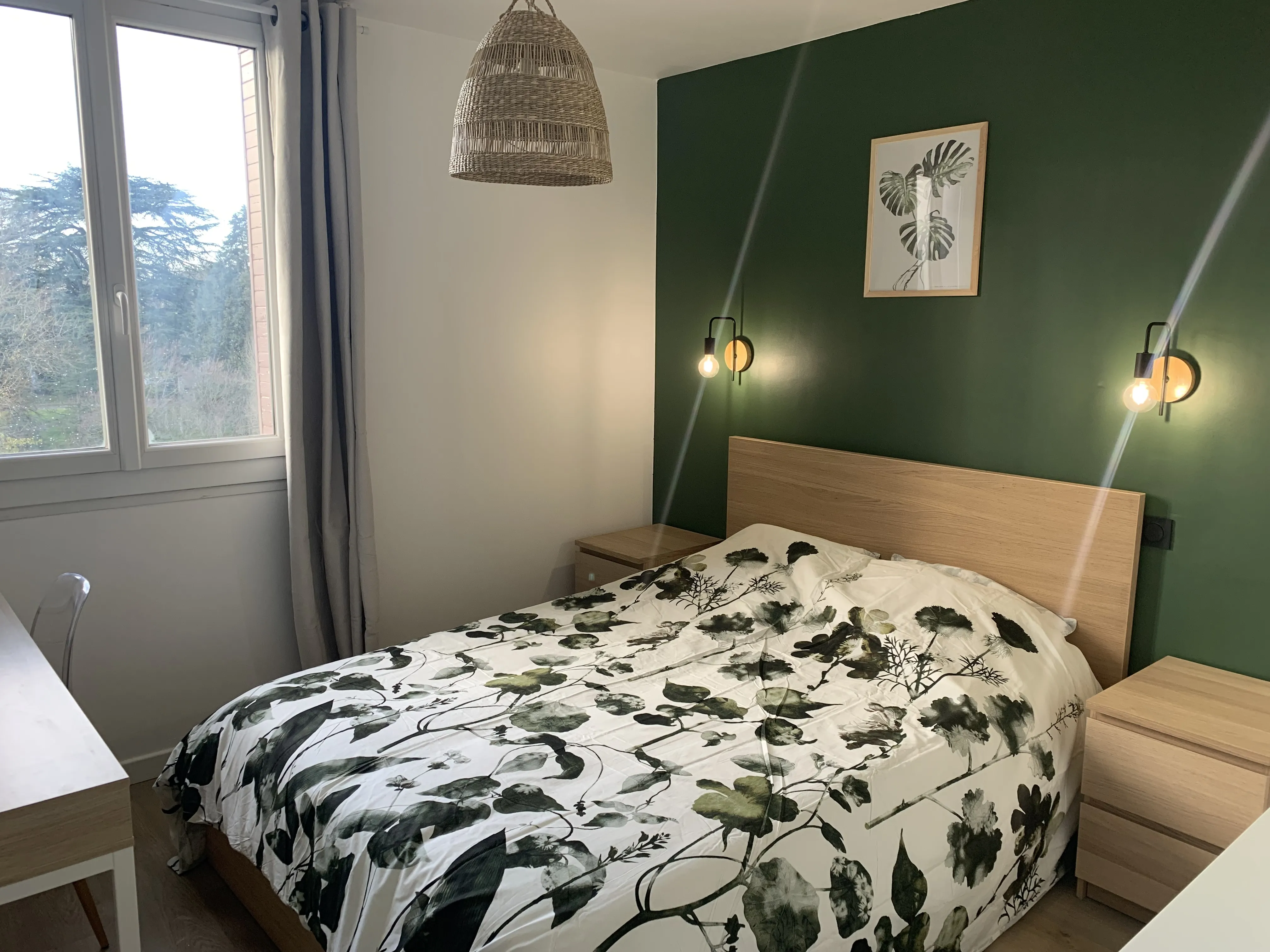 Lit double avec tête de lit en bois, appliques et mur vert sapin