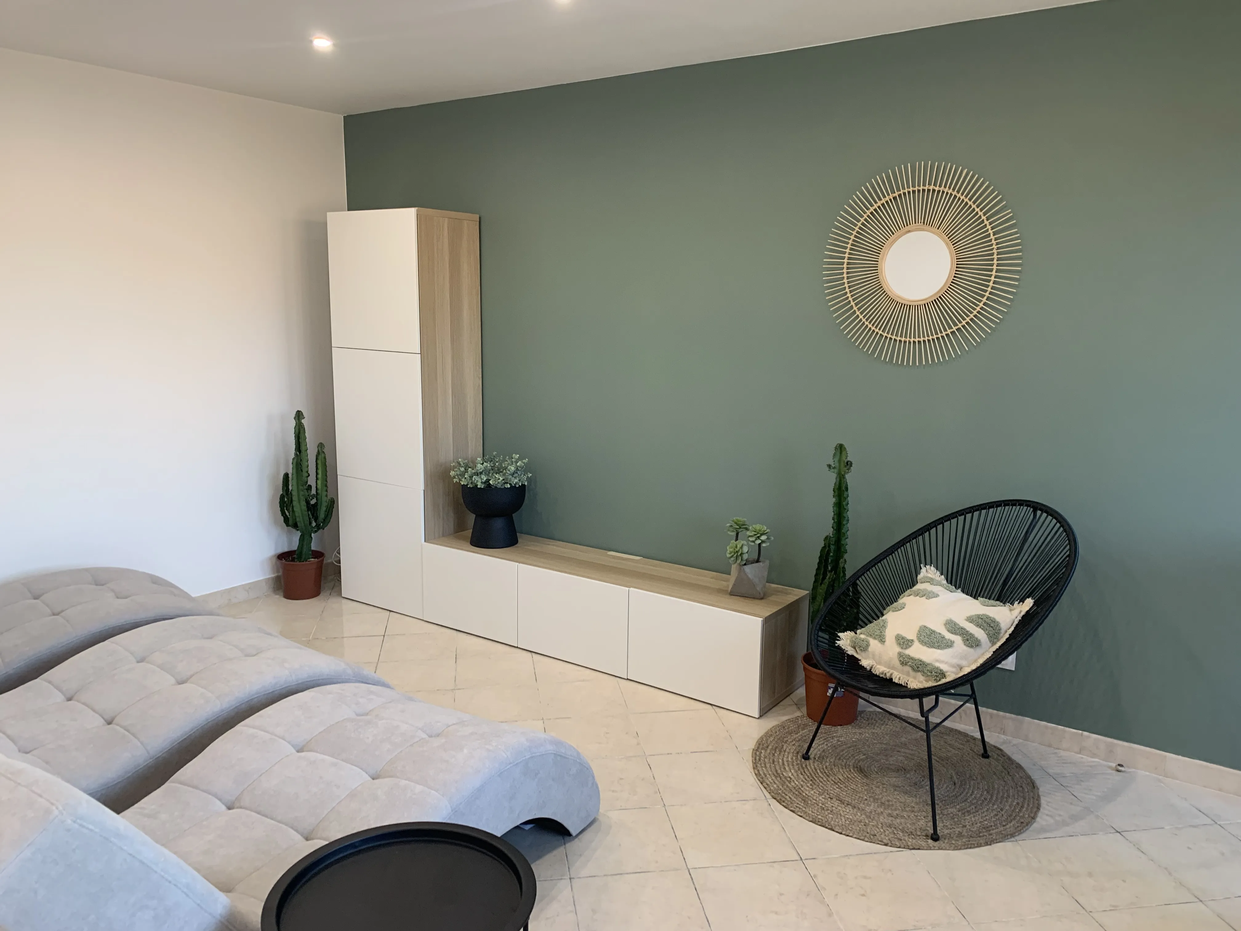 Espace détente avec canapé, meuble TV et mur vert sauge